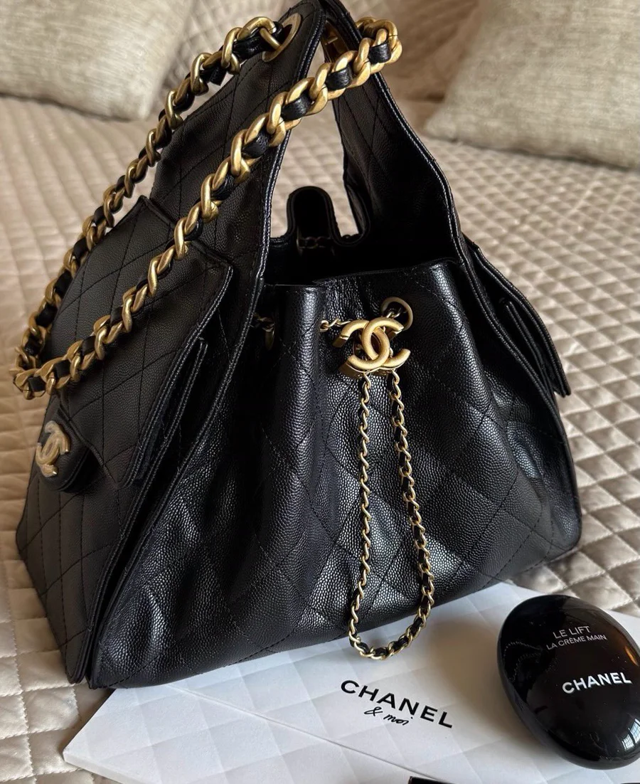 Bolsa bucket preta em couro caviar acolchoado com corrente e pingente dourado