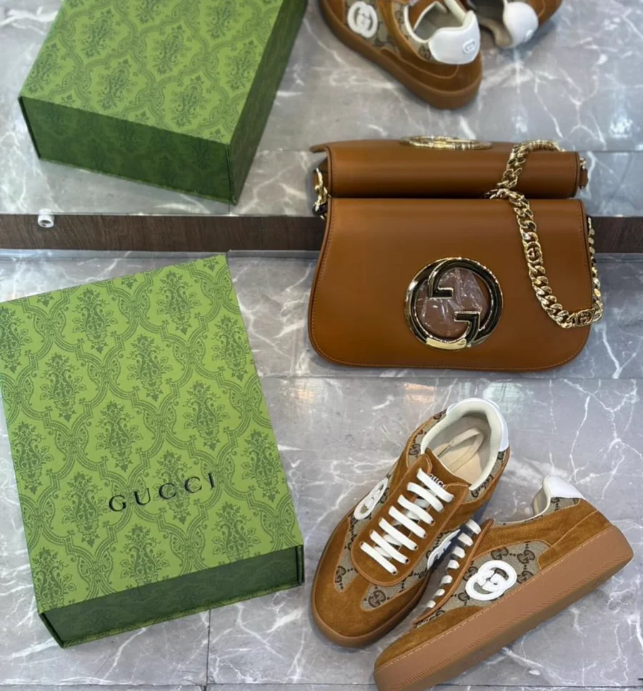 Bolsa em couro caramelo liso com fivela circular dourada e corrente